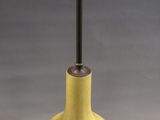 a yellow vase with a metal handle on a table