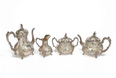 four pieces of silver tea and coffee set on a white surface