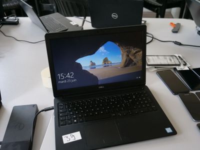 un ordinateur portable posé sur une table, à côté d'un téléphone portable