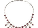 a necklace with pink stones and silver chains on a white background