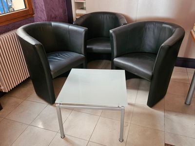 deux fauteuils en cuir noir et une table blanche dans un coin de la pièce