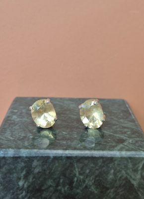 une paire de boucles d'oreilles en topaze jaune posées sur un socle en marbre