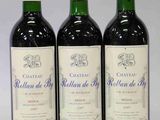 trois bouteilles de vin rouge sont alignées sur une surface blanche