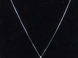 Un collier orné d'une perle blanche est accroché à un mannequin noir