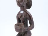 une vieille figurine en bois représentant une femme tenant un bol