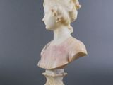 a white marble bust of a woman on a pedestal