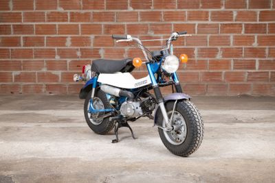 a blue and white motorcycle parked in front of a brick wall