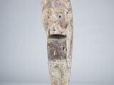 a wooden sculpture of a head on a black stand