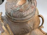 bronze statue of a woman holding a vase with a bird perched on top of it