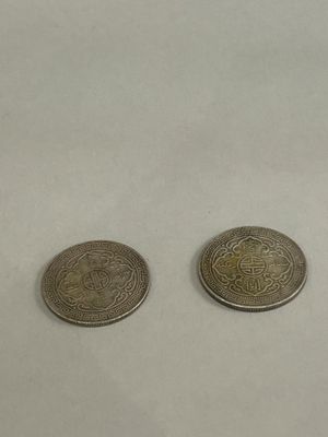 two coins sitting on top of a white surface next to each other