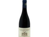 the bottle of red wine is sitting on a white surface