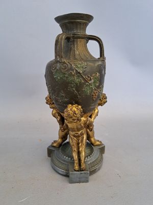un vase en bronze orné d'un lion, posé sur un socle