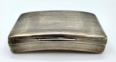 un étui à cigarettes ancien en argent posé sur une surface blanche