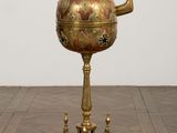 brass teapot on stand on wooden floor with white wall in background