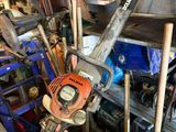 un homme tenant une tronçonneuse dans un garage