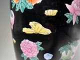 a black vase with colorful flowers painted on it
