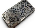 a silver cigarette case sitting on a white surface