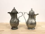 two silver coffee pots sitting on a wooden table