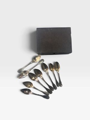 a set of six spoons and a box on a white surface