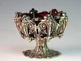 a silver bowl with garnets in it on a table