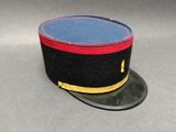 un chapeau noir et bleu avec une bordure rouge, posé sur un chapeau noir