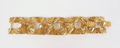 gros plan d'un bracelet en or sur une surface blanche
