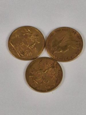 three gold coins sitting on top of each other on a white surface