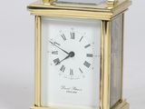 une petite horloge en or avec une clé posée devant