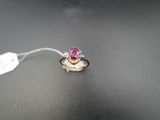 une photo d'une bague sertie d'un saphir rose et de diamants, posée sur une surface noire