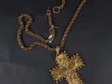 un collier en or orné d'une croix, posé sur une table