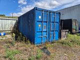 un conteneur bleu posé au milieu d'un champ