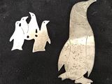 un pingouin en métal argenté et deux pingouins sur fond noir