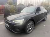 a black audi suv parked in a parking lot next to a fence