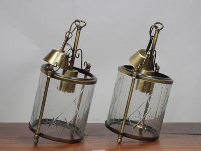 une paire de lanternes anciennes en laiton et en verre posées sur une table en bois