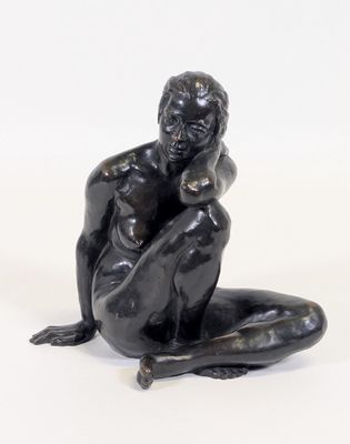 une sculpture noire représentant un homme assis par terre, les mains posées sur les genoux
