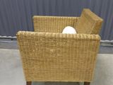 a wicker chair with a pillow on it in front of a metal wall