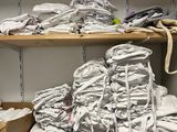 de nombreuses piles de linges blancs pliés sur les étagères