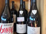 several bottles of wine sit in a wooden box on a shelf