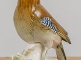 porcelain figurine of a bird sitting on a branch with leaves