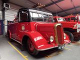 a red fire truck parked in a garage next to other fire trucks