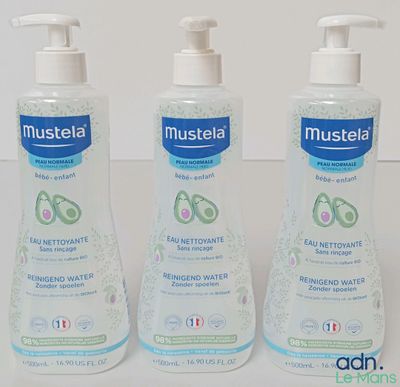 trois flacons de gel hydroalcoolique Mustela posés sur une table