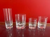 four shot glasses sitting on a table with a red wall in the background