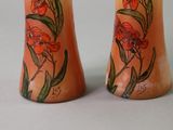 two vases with flowers painted on them sitting on a table