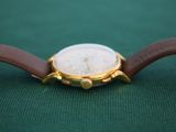 a close up of a watch on a green surface
