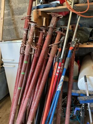 de nombreuses battes de baseball empilées sur une étagère dans un garage