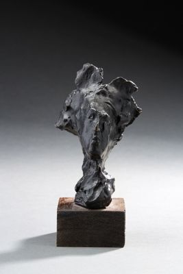 statue représentant une tête d'éléphant posée sur un socle en bois, sur une surface blanche