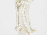 une statue blanche représentant une femme tenant un enfant dans ses bras, posée sur un socle en bois