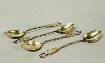 four antique spoons are sitting on a table next to each other