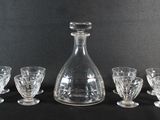 une image représentant une carafe en verre et quatre verres sur fond noir