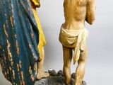 une statue représentant un homme tenant une croix, à côté d'une statue représentant une femme